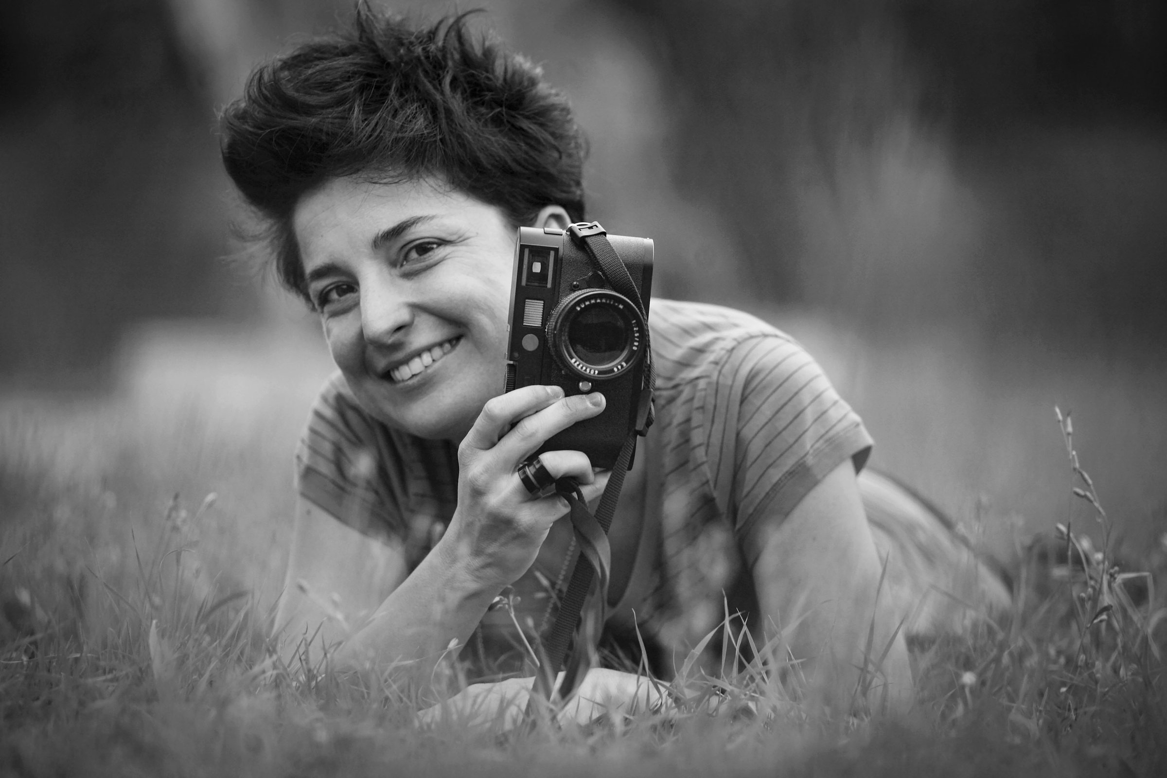 Azzurra Primavera sdraiata sull'erba con una fotocamera in mano